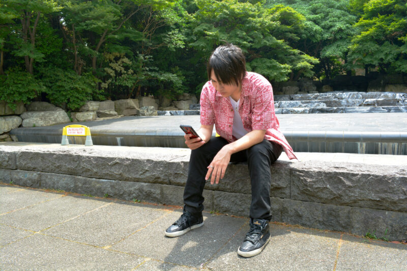 公園でスマホをいじる男性