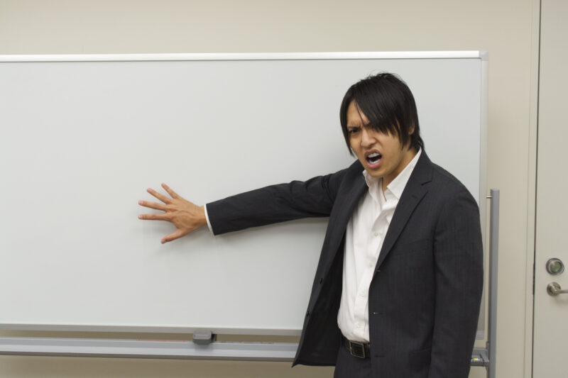 ホワイトボードを指しながら怒るビジネスマン