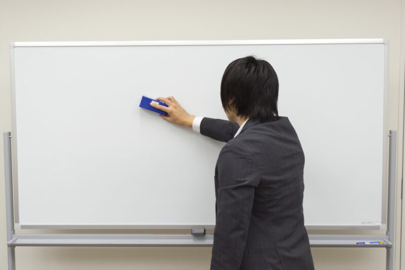 ホワイトボードを消しているビジネスマン
