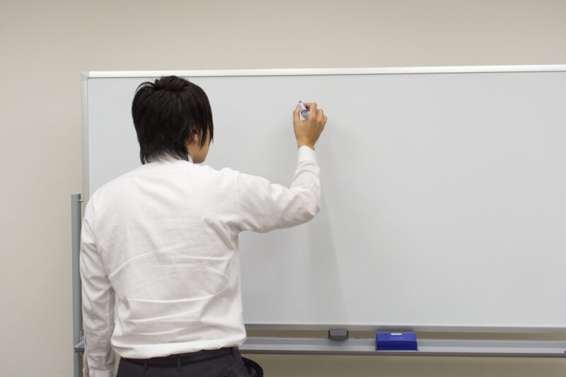 ホワイトボードに書き込む後ろ姿のビジネスマン