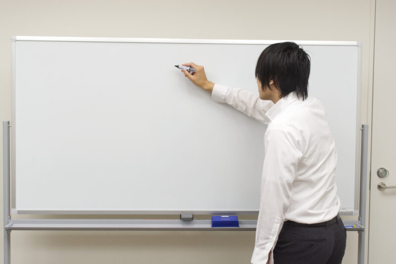 ホワイトボードに書き込む白いシャツのビジネスマン