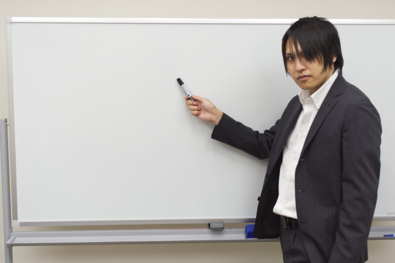 真剣な表情でホワイトボードを指すビジネスマン